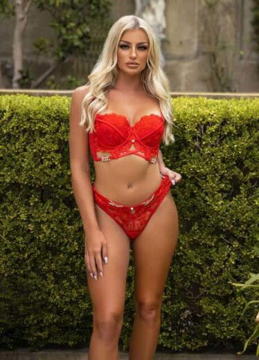 in a playful pose, blonde model ellie b in a red bikini with hands on her hips