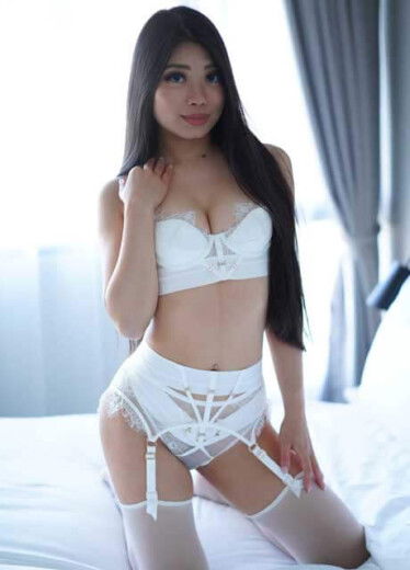 a captivating asian topless waitress in sydney with a brunette hairstyle named gemini laying on  white beding